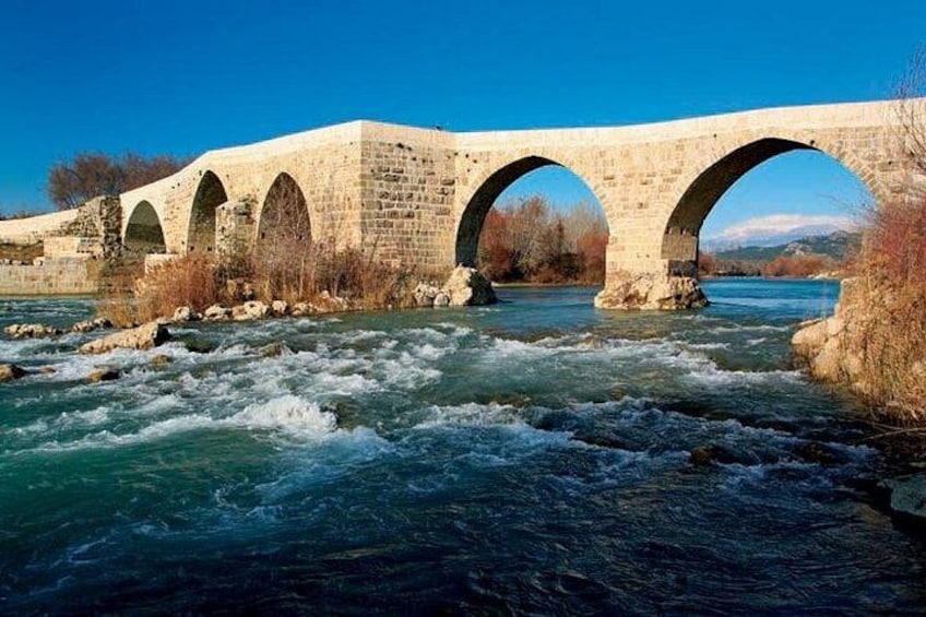 A stone bridge with multiple arches over a flowing river. 3