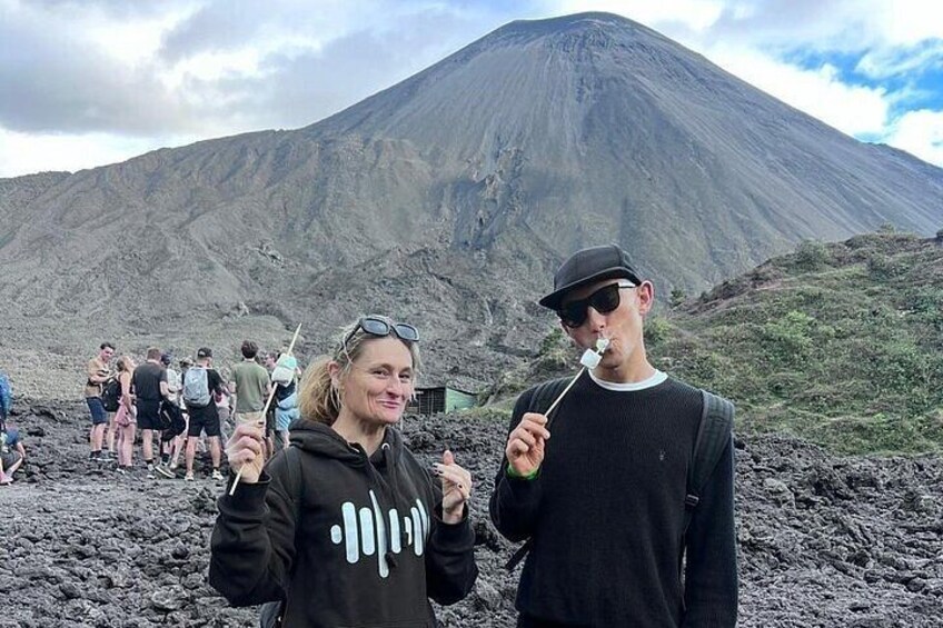 Two people standing in front of a volcano with a group of people in the background. 3