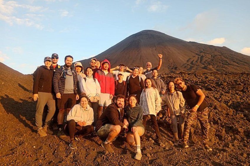A group of people posing in front of a volcano. 4