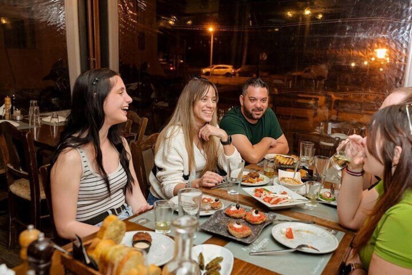 Un grupo de personas cenando en un restaurante con varios platos sobre la mesa. 5
