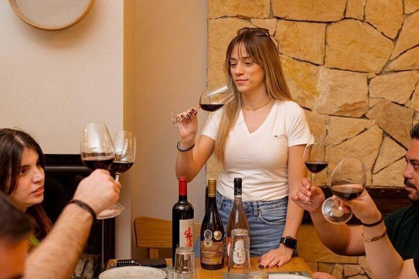 A group of people sitting at a table with wine bottles and glasses. 3