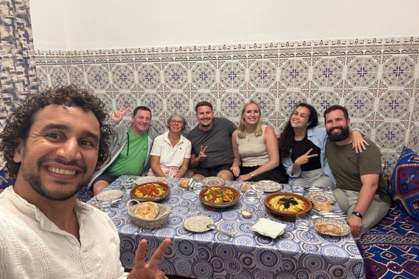 Un groupe de personnes est assis autour d’une table, devant différents plats. 2