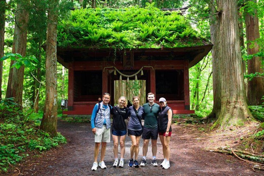 Un grupo de personas frente a una estructura tradicional japonesa rodeada de un bosque. 5