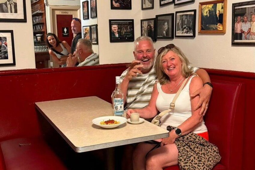 A diner with red booths, a table with a plate of food, a bottle of water, and a cup. 3