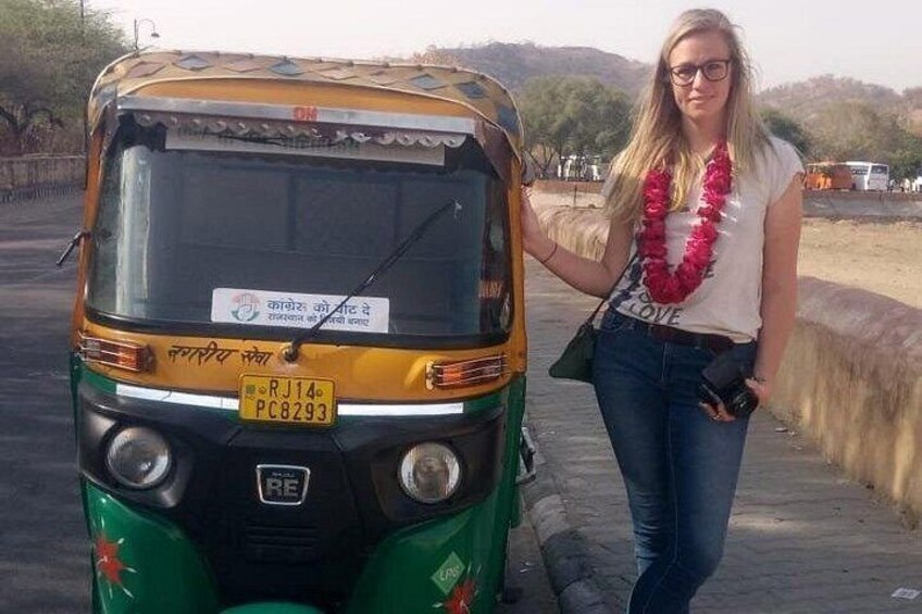 A woman standing next to a green and yellow auto-rickshaw with a license plate. 5