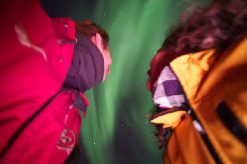 Une personne portant une veste rouge et une autre portant une veste jaune, toutes deux observant les aurores boréales. 5