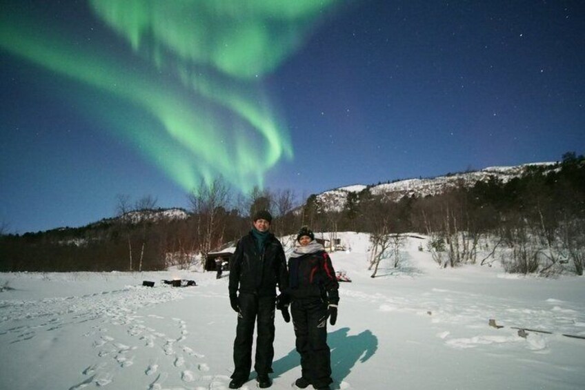 Zwei Personen stehen in einem verschneiten Feld, während das Polarlicht am Himmel erscheint. 3