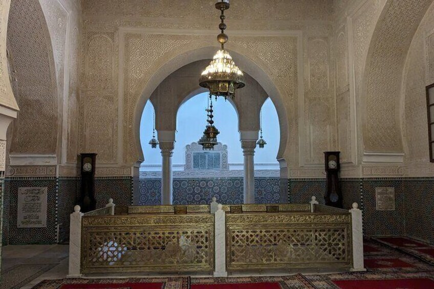 An ornate interior with a central archway, a chandelier, and a view of a building outside. 2