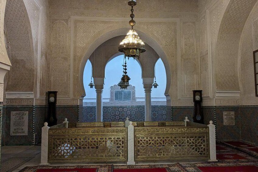 An ornate interior with a central archway, a chandelier, and a view of a building outside. 2