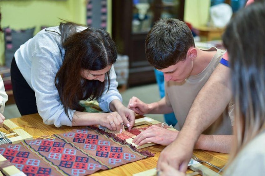 People engaged in a craft activity, possibly quilting, with a patterned fabric on the table. 1