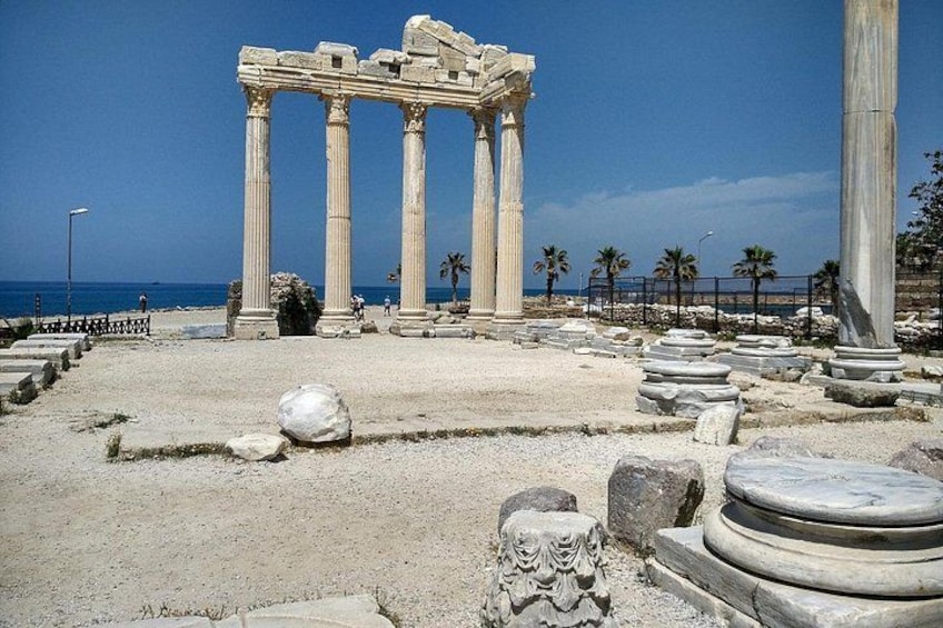 Ancient ruins with columns, palm trees, and a clear sky. 2