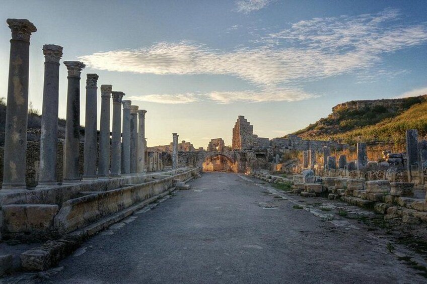 Ancient ruins with columns and a pathway leading to a distant structure. 1