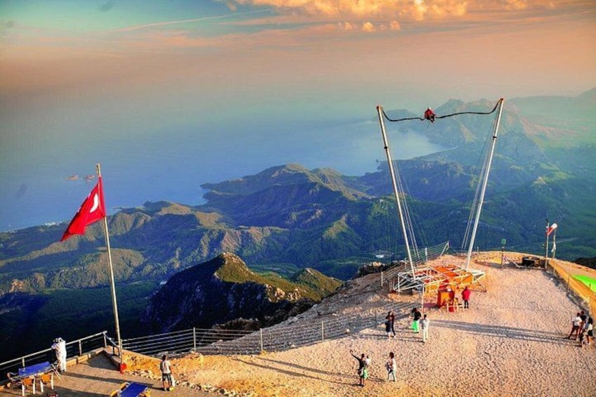 A mountainous landscape with a suspension bridge, a red flag, and a rocky terrain. 2