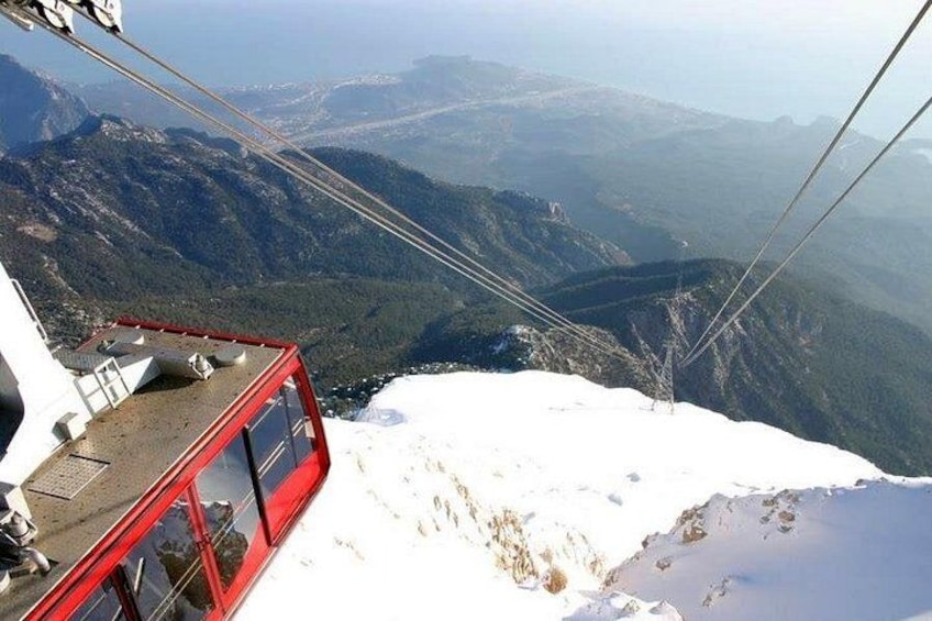 A cable car on a snowy mountain with a view of the valley below. 4