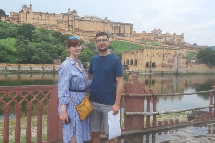 Una pareja de pie frente a una fortaleza histórica, con un río al fondo. 2