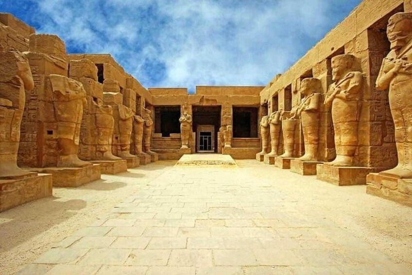 A courtyard with large stone statues and a clear sky. 2