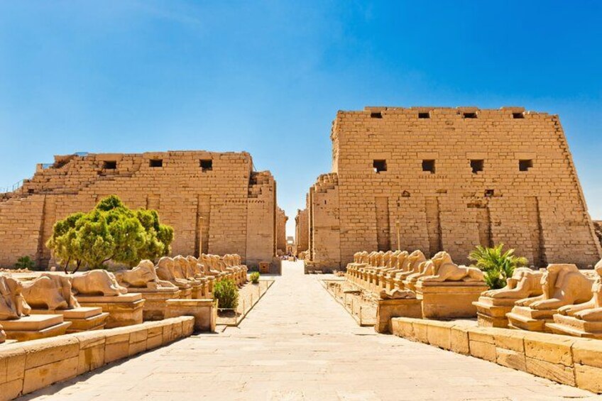 A pathway leading to a large ancient structure with a clear sky above. 1