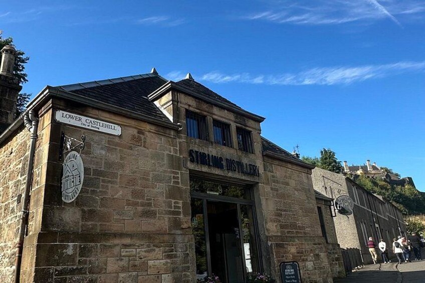 Een stenen gebouw met een bord waarop 'Lower Castlehill' en 'Stirling Distillery' staan. 4