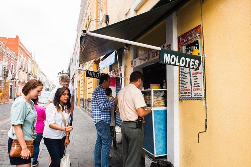 A street food vendor named 'MOLOTES' with a menu board and a customer interacting. 1