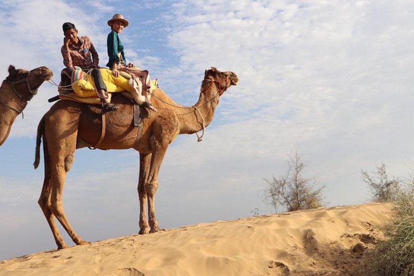 Two people riding a camel on a sandy dune. 4