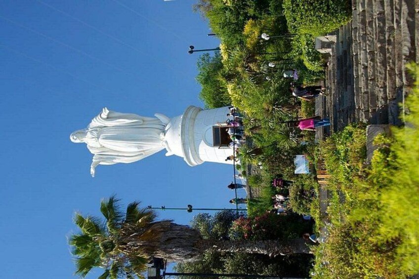 Una estatua blanca grande en un parque, con palmeras y gente alrededor. 1