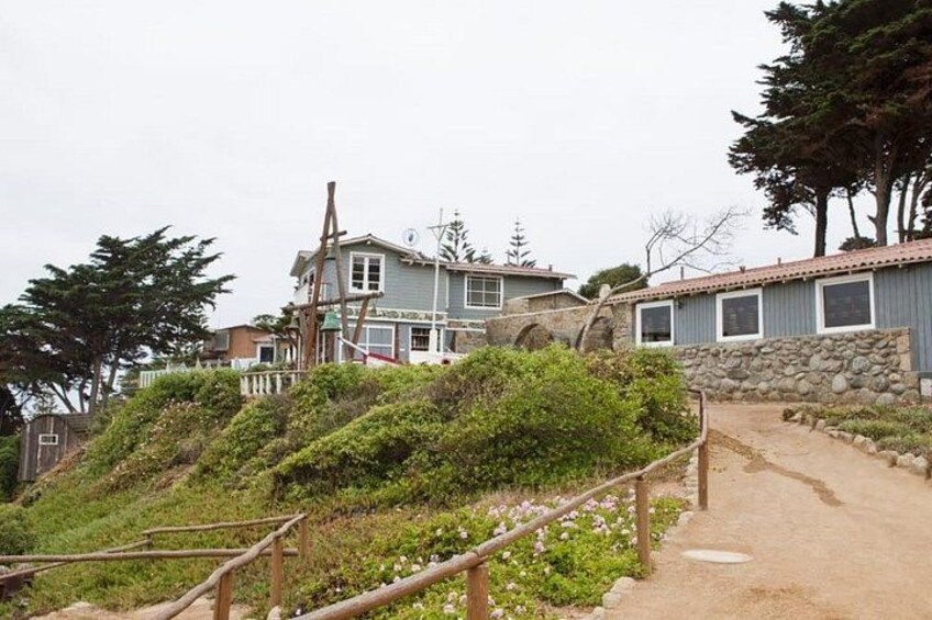 A coastal residential area with houses, a dirt path, and a wooden fence. 2