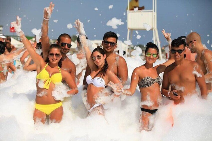 People in a beach setting with foam and water. 2