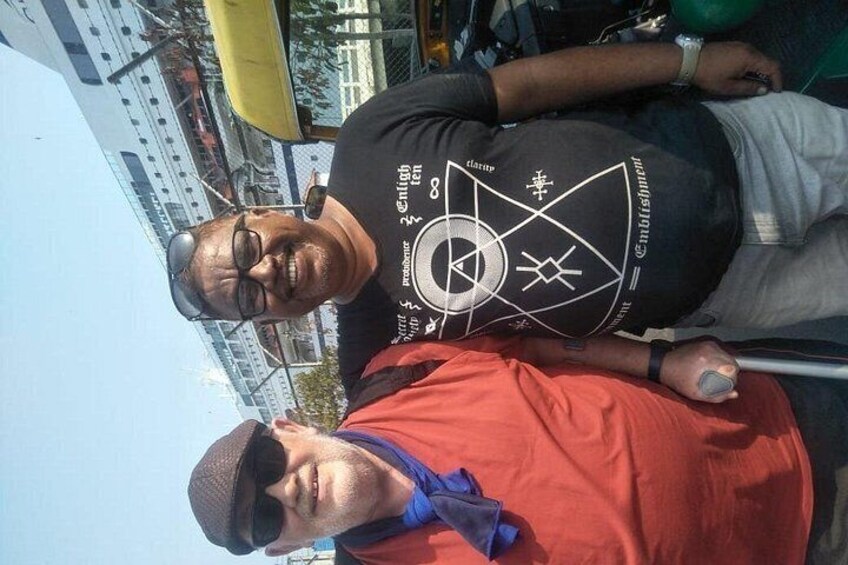 Two people standing outdoors, one wearing a black t-shirt with a white graphic and the other in a red t-shirt. 4