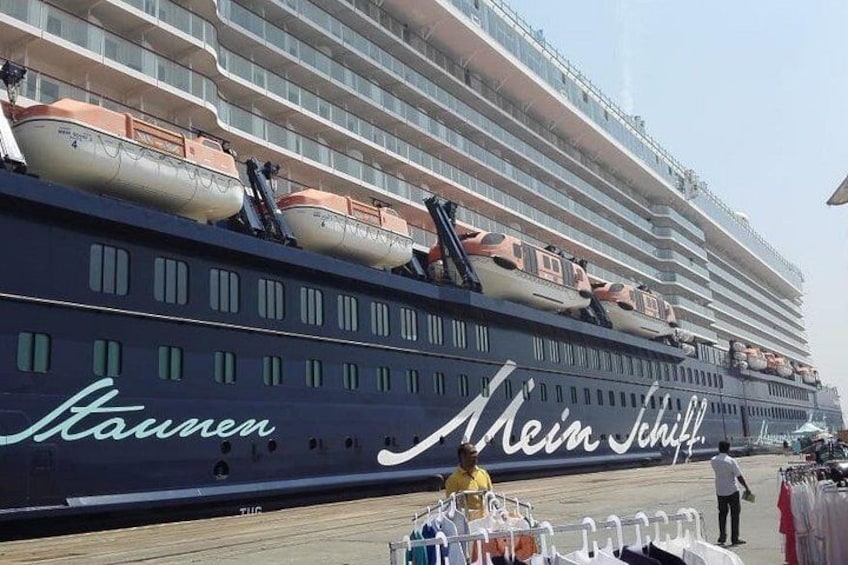 Un grand navire de croisière, le « Kauwer », était amarré dans un port, avec un bâtiment visible en arrière-plan. 3