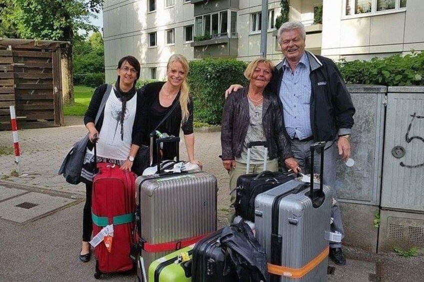 Quatre personnes avec des bagages, un bâtiment et une clôture. 5