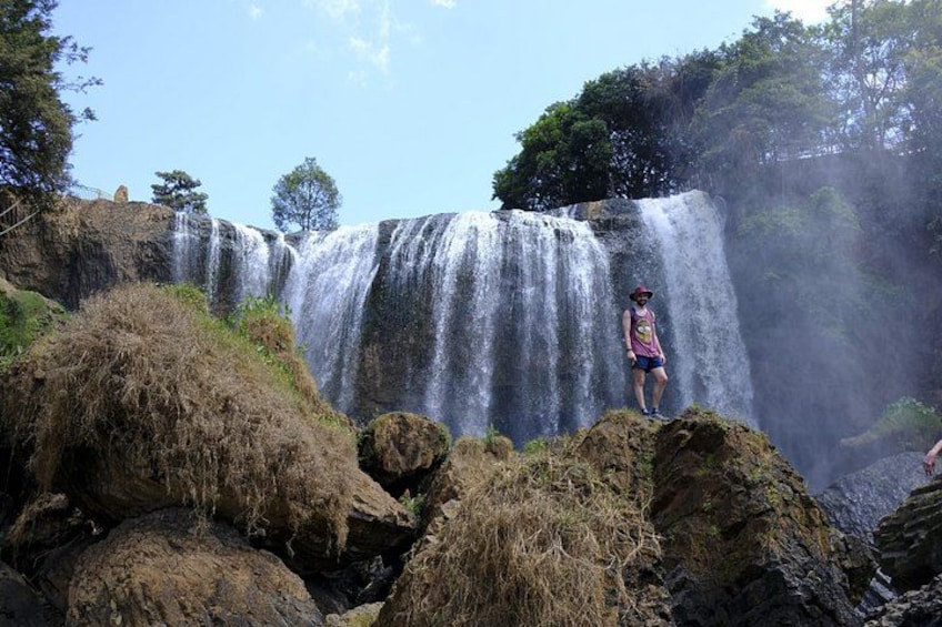 A waterfall with a person standing on rocks in the foreground. 5