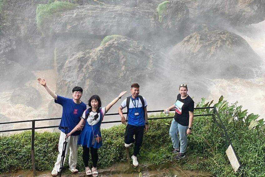 A group of people standing on a ledge with a rocky landscape and greenery in the background. 5