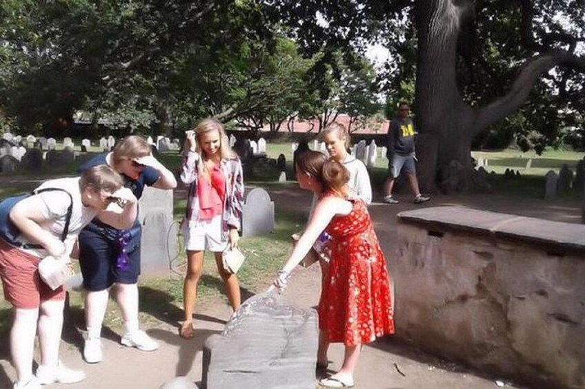 Eine Gruppe von Menschen auf einem Friedhof, im Hintergrund Grabsteine. 2