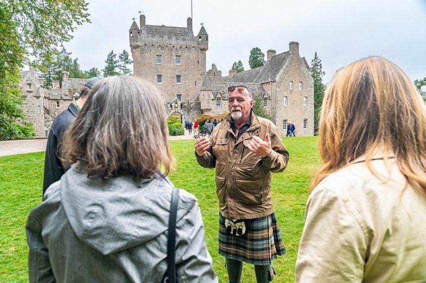 A historical building with a castle-like structure, a person in traditional attire, and a group of people in a grassy area. 3
