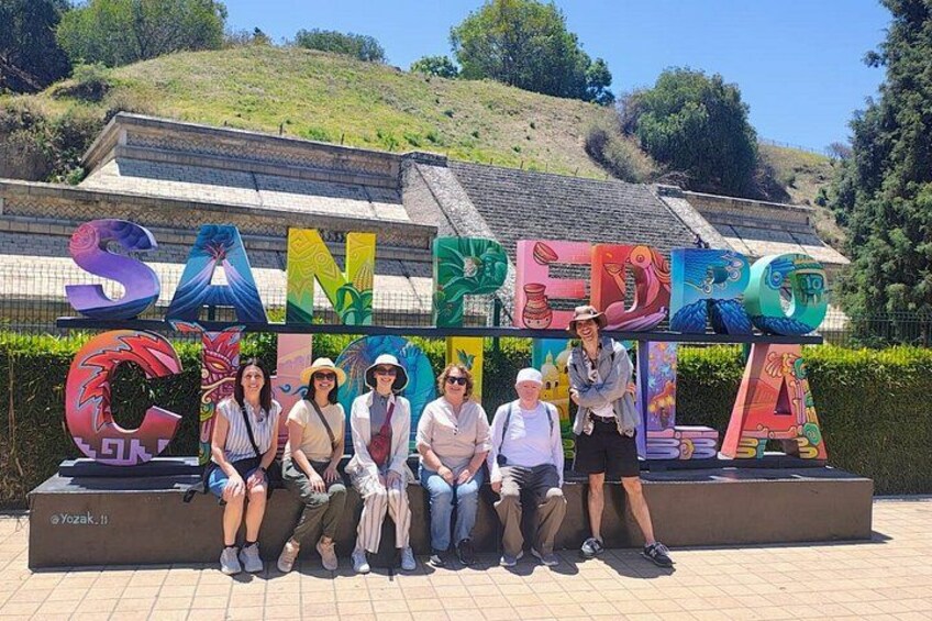 Un grupo de personas posando frente a un letrero colorido que dice 'SAN PEDRO CANTERA'. 3