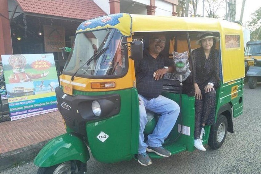 A green and yellow auto-rickshaw with two passengers. 5