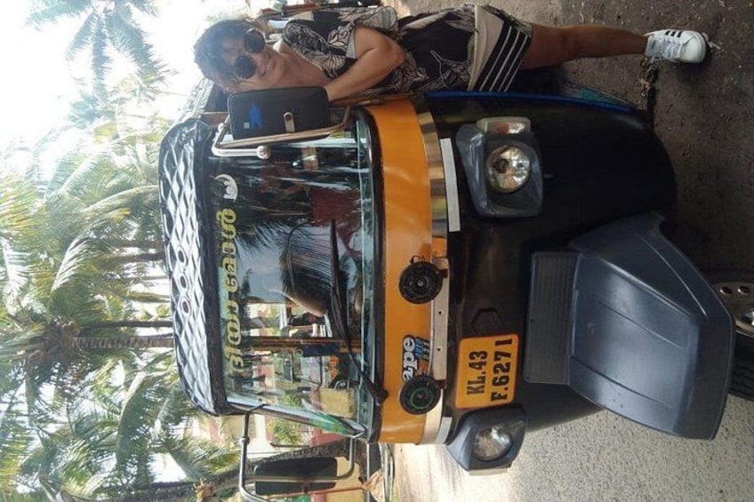 A yellow bus with a black and white design, a license plate, and a person sitting on the front. 2