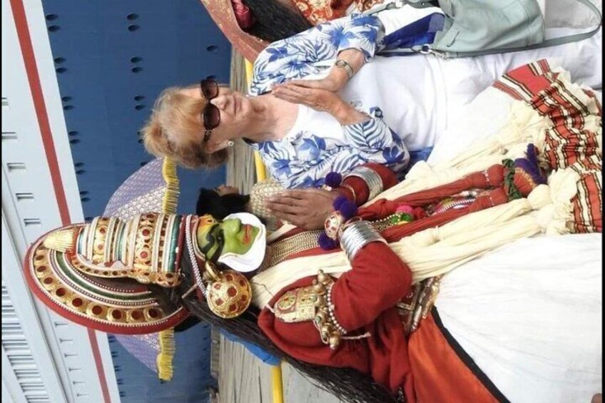 A person in traditional attire with a decorated headpiece and jewelry, lying on a bed with a patterned blanket. 3