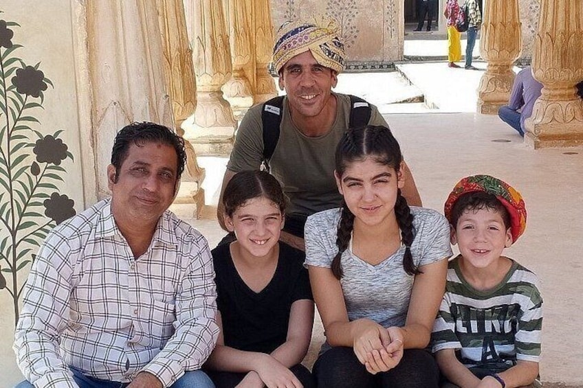 A family of four sitting in a courtyard with ornate columns and floral decorations. 2