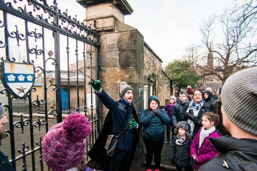 A group of people gathered outside a building with a metal gate, some wearing winter clothing. 5
