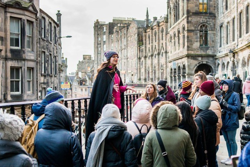 A crowd gathered on a city street with historic buildings in the background. 1
