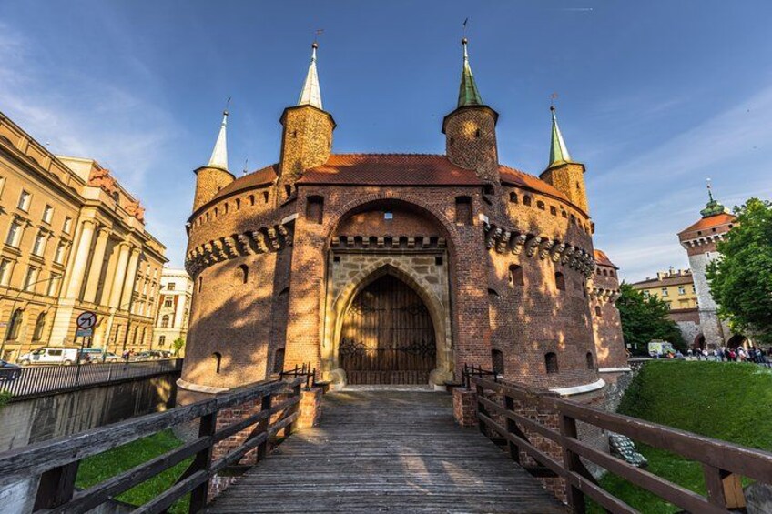 A historic brick castle with a large wooden gate, a wooden bridge, and a clear blue sky. 1