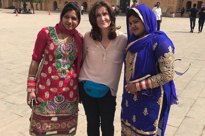 Three people standing in a courtyard with a tiled floor and a building in the background. 2