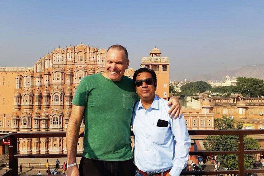 Two people standing in front of a large, ornate building with a tower. 4