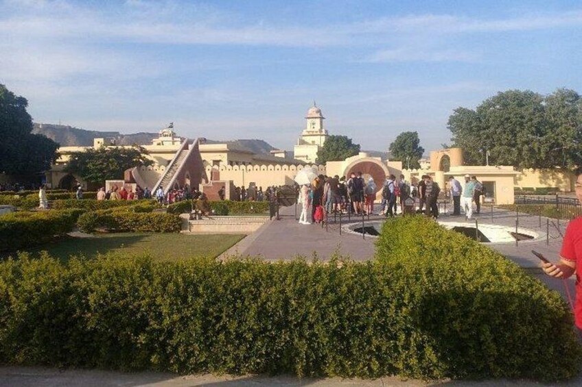 A historical building with a staircase, a crowd of people, and a well-maintained garden. 2
