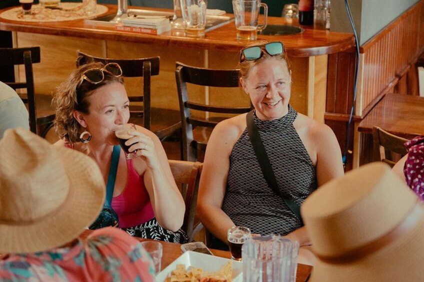 People sitting at a wooden table in a restaurant with food and drinks. 2