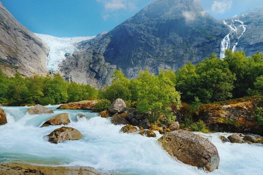 Une rivière parsemée de rochers, une cascade et un glacier en arrière-plan. 3