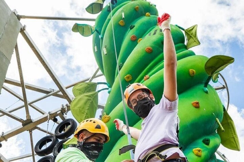 A person climbing a large inflatable structure with green and yellow colors and leaf-like shapes. 1