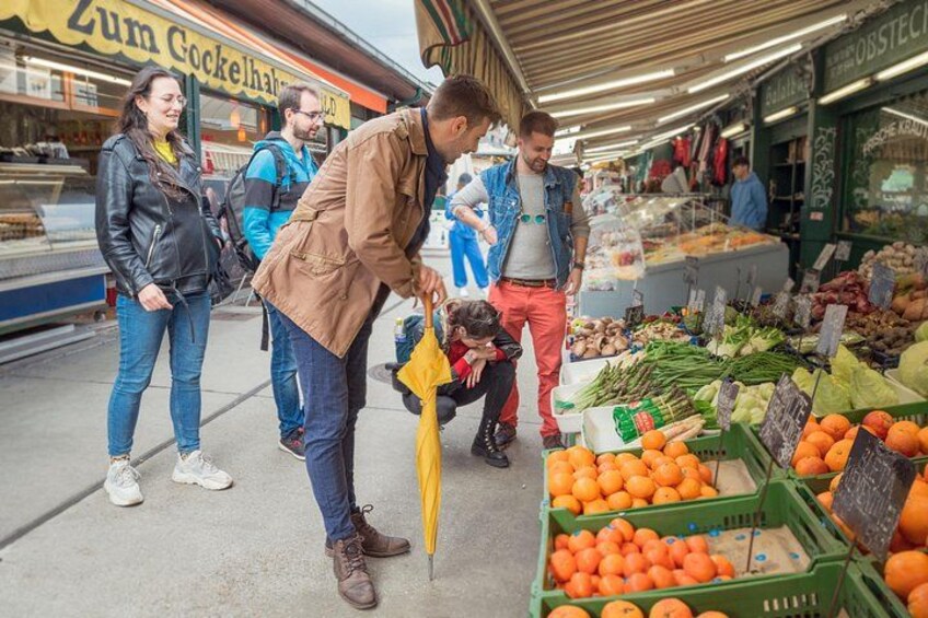 A market scene with people shopping and a vendor selling oranges. 4