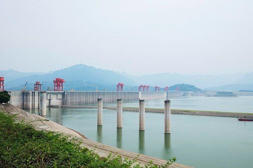 A dam with water gates, a wooden walkway, and mountains in the background. 4